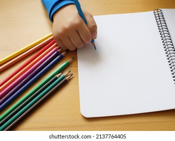 Hand Of A Four Year Old Boy Drawing On Blank Page With Colored Pencils