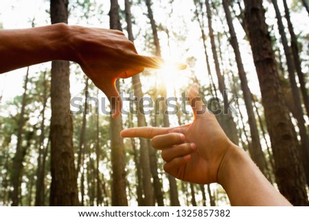 hand framing distant view  over sunsrise in forest