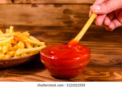 Hand With Fresh French Fry Dipped Into Tomato Sauce