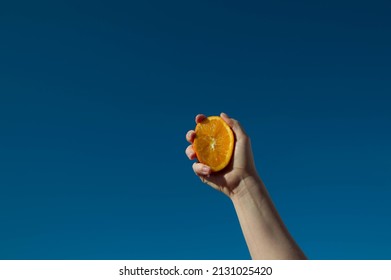 Hand With Fresh Orange Fruit On Blue Sky Background