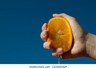 Hand With Fresh Orange Fruit On Blue Sky Background