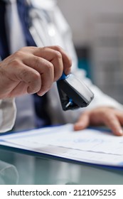 Hand Of General Practitioner Using Medical Stamp On Prescription Paper. Health Care Specialist Putting Seal On Checkup File To Give Treatment To Patient At Consultation. Close Up