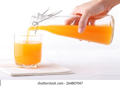 Hand Gently Pour Orange Juice From Vintage Bottle Into A Glass