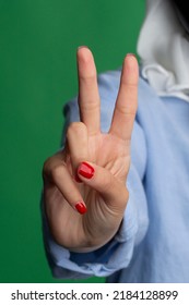 Hand gesture, female with red nail polish, on a green background. 