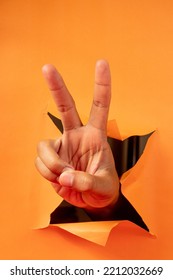 Hand Gesture On Torn Orange Paper Background