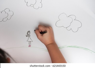 A hand of a girl drawing lines and shapes with colorful pencil. Her drawing look like the family's members. - Powered by Shutterstock