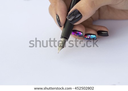 The hand of a girl holding a black pen with the pen in the position of writing