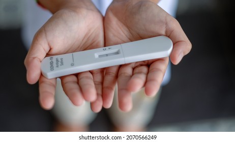 Hand Of A Girl Holding A Covid-19 Antigen Saliva Test Kit . Negative Test Result