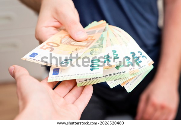 Hand gives bunch of Euros to other hand. Old\
style money transfer. Paying for services. Street  economy. Urban\
lifestyle.