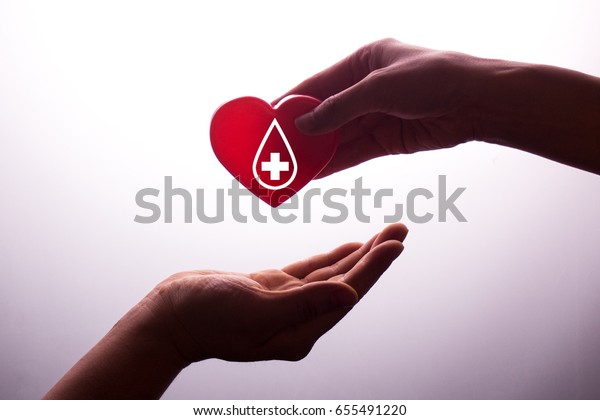 A hand gives a red heart to a hand - blood\
donation,world blood donor\
day