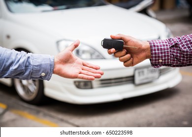 Hand Giving Car Key On Car Background