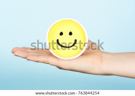 Hand giving hapiness concept. Yellow happy face emoticon.
