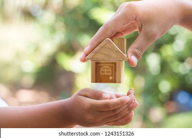  hand is giving a model of a house to child's hand, Concept for Investing in long-term real estate for the future. - Shutterstock ID 1243151326