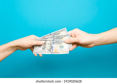 Hand Giving One Hundred Dollar Bills And Hand Taking Money, Blue Background. The Concept Of Salary, Loan, Credit, Money Circulation