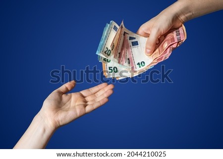 Hand giving some money euros isolated. Blue background. High quality photo
