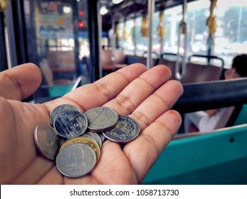 Hand giving Thai baht to pay for the bus - Shutterstock ID 1058713730