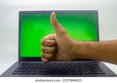 A hand giving a thumbs up in front of a laptop with a green screen, isolated on a white background. Perfect for approval, positivity, or technology concepts - Powered by Shutterstock