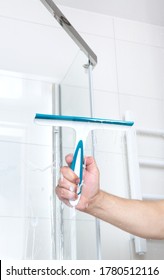 Hand With Glass Scraper Cleans Glass In Shower. High Quality Photo