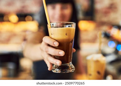 Hand, glass and serving ice coffee, alcohol or cocktail beverage with straw at cafe bar. Closeup, bartender and giving latte to woman for cold brew or drink order at happy hour for hospitality at pub - Powered by Shutterstock