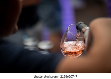 hand with a glass of rosé wine at a wine tasting - Shutterstock ID 2138620747