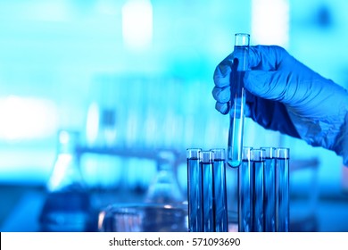 Hand in glove holding test tube on blurred background