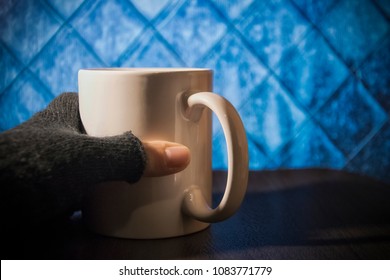 A hand in a glove holding a white cup