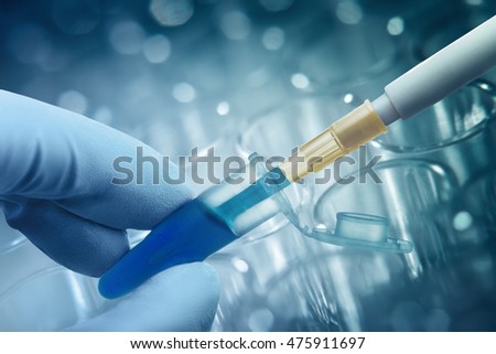 Hand in glove keeps plastic tube with dipped pipette, plastic plate for immunosorbent assay on background