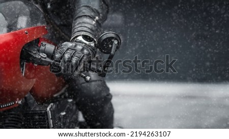 Hand in glove on motorcycle handlebar in winter, free space for insertion