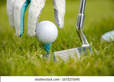 Hand In Glove Placing Golf Ball On Tee