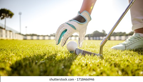 Hand In Glove Placing Golf Ball On Tee