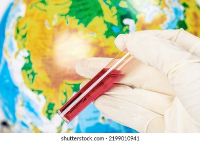 Hand In Glove With A Test Tube Of Blood On A Background Of The Globe