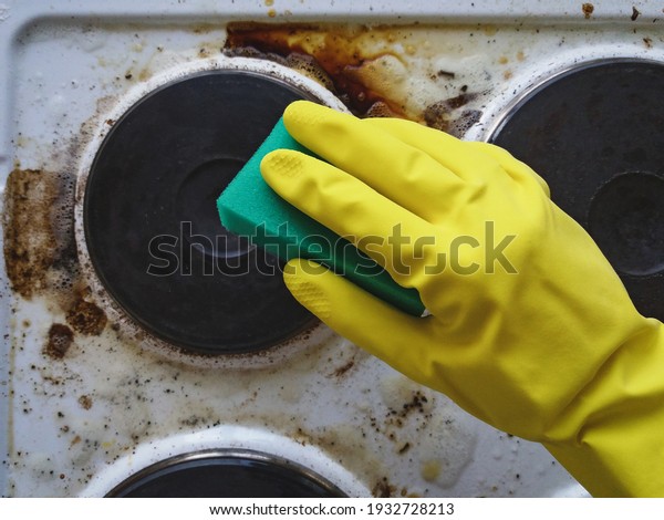 Hand in glove\
washing messy kitchen\
stove