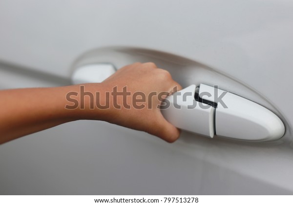 A hand is going\
to pull a car\'s door handle