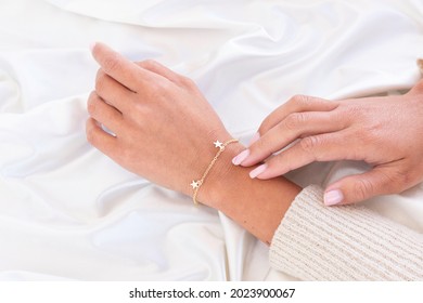 hand with gold bracelet with stars and hand touching from behind