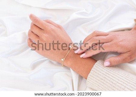 hand with gold bracelet with stars and hand touching from behind
