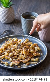 A Hand Grabbing With A Fork Gluten-free, Shredded Pancake / Kaiserschmarrn Served With Halvah Spread, Banana, Walnuts, And Grated Chocolate Placed On A Decorative Plate And Teacups At The Background