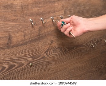 Hand Grabbing Keys From Hook On Wooden Wall