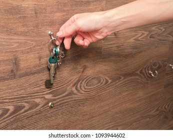 Hand Grabbing Keys From Hook On Wooden Wall