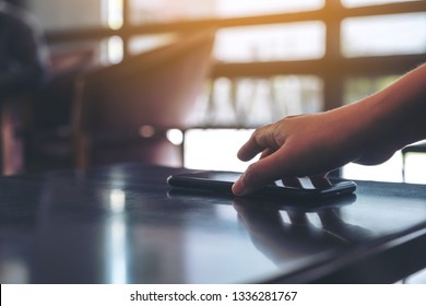 A Hand Grabbing And Picking Up Mobile Phone On The Table 