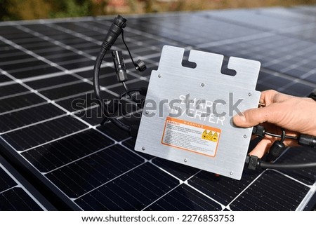 hand grabs smart micro inverter in front of photovoltaic system. Beautiful banner with blurred background