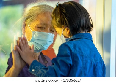 Hand of the grandma and grandchild on a window plane,Protection coronavirus and covid-19 pandemic,Social distancing concept.