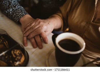 Hand of grandmother and grandson on the table near the cup of coffee, grandson visiting grandmother - Powered by Shutterstock