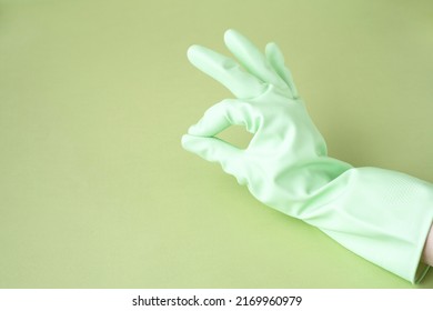 Hand In Green Rubber Glove Showing Ok Symbol On Green Background For Design With Copy Space. Concept For Cleaning, Medicine, Sanitize, Hazardous Production.