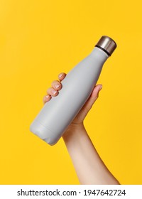 Hand with grey reusable insulated bottle on yellow background. Zero waste, plastic free and sustainable lifestyle concept - Shutterstock ID 1947642724