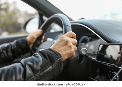 hand gripping a steering wheel while driving a car, focused and in control - Powered by Shutterstock