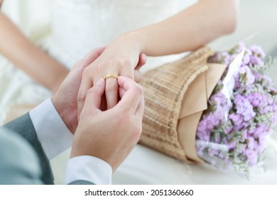 Hand of The groom wears a wedding ring to the bride.