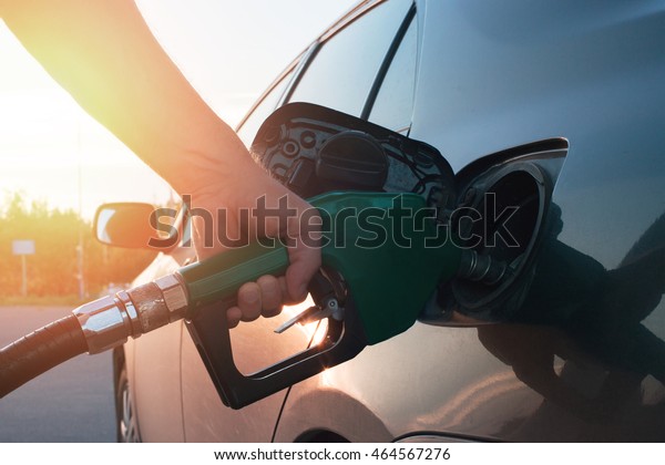hand guiding the fuel in the gasoline tank of\
the car at a small depth of\
field