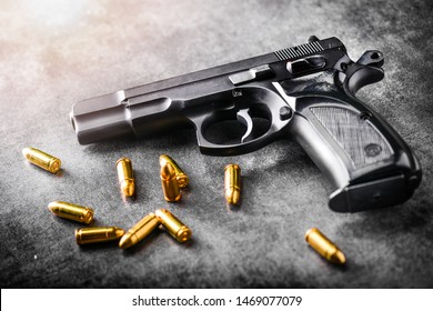 Hand gun with ammunition on dark stone background. 9 mm pistol gun military weapon and pile of bullets at the metal table.
