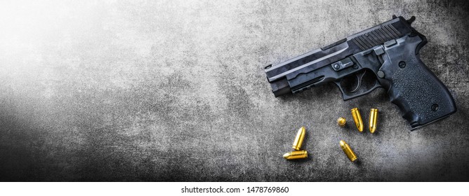 Hand gun banner or panorama pfoto on dark stone table top view. Ammunition or bullets at black background. Copy space for text concept.