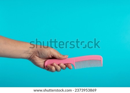 Hand and hair comb isolated on blue background